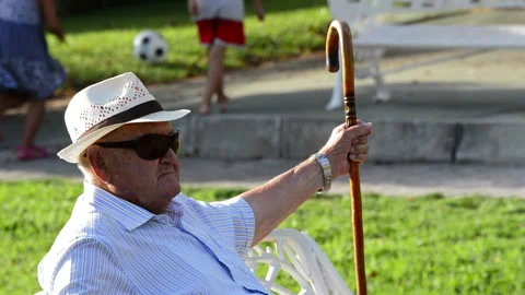 Senior man with walking stick sitting in park 4K Stock Footage 340878305