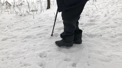 Senior man with walking stick walking hard on a snow covered path Stock Footage 150028552