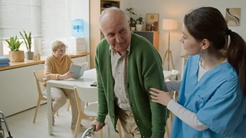 Senior Man Walking with Walker Assisted by Female Nurse in Nursing Home Stock Footage 337619642
