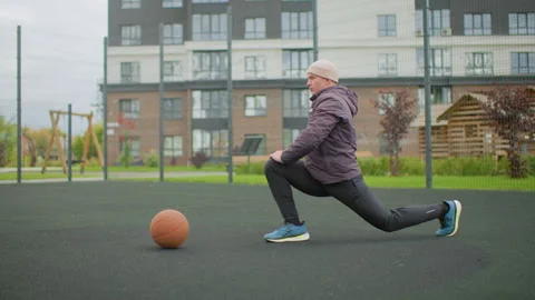 Senior man warms up outside, Senior gentleman engaging in outdoor fitness Stock Footage 329436827