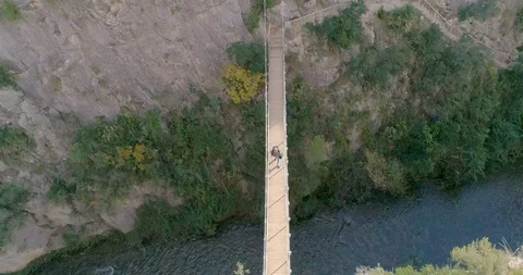 Senior man with white beard crossing a suspension bridge over ravine Stock Footage 124388070