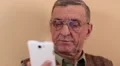 Senior man with white smartphone speaks and smiles HD Footage