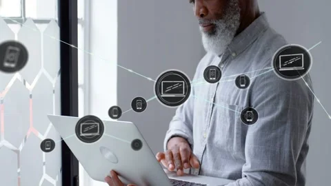 Senior man by window tapping laptop, creating IT network nodes and icons Stock Footage 330740959