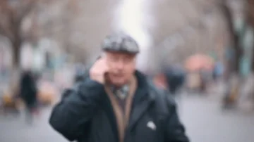 A senior man in a woollen flat cap walks and calls on an alley in autumn. Stock-Footage 85525863