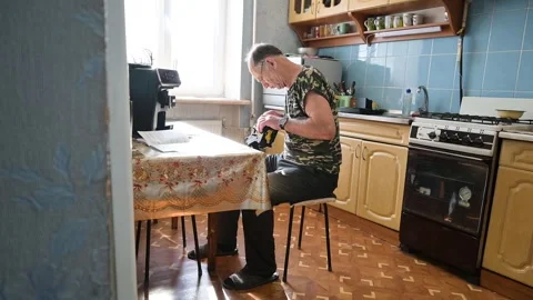 Senior man working and fixing small device on a kitchen table at home Stock Footage 345638205