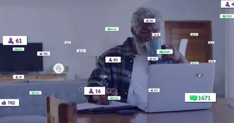 Senior man working and sipping mug while social badges appearing crowding laptop Stock Footage 334115570