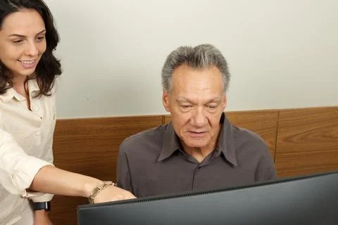 Senior man working on a computer with a young woman Stock Photos