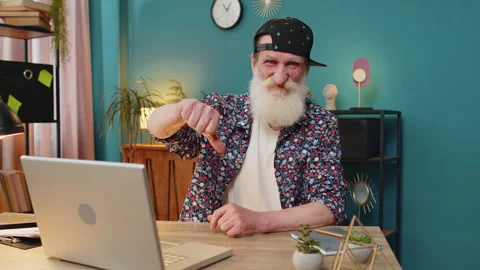 Senior man working on laptop computer at home office showing thumbs down sign Stock Footage 279728967