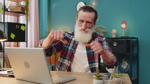 Senior man working on laptop computer at home office showing thumbs down sign Stock Footage 311606221
