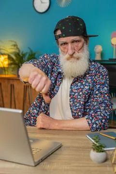 Senior man working on laptop computer at home office showing thumbs down sign Stock Photos