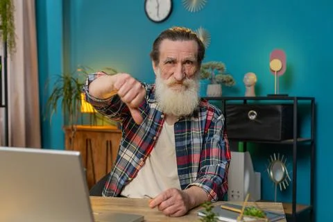 Senior man working on laptop computer at home office showing thumbs down sign Stock Photos