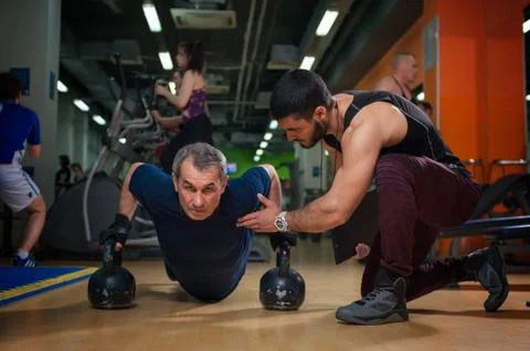 Senior man working with personal trainer in gym Stock Photos