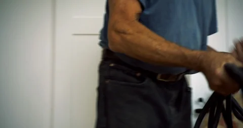 Senior man wrapping up a power cord. 库存影片 88375647