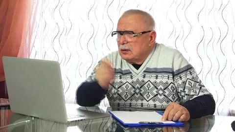 Senior man writes down information from laptop screen Stock Footage 108130653