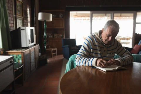 Senior man writing at table Stock Photos
