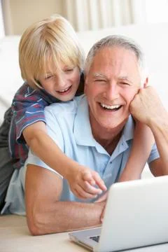 Senior man with young boy using laptop computer 스톡 사진