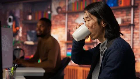 Senior manager drinks coffee while working in software development agency 写真素材