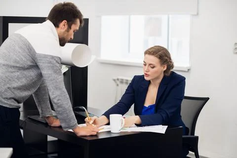 A senior manager explaining something to her team member, while Stock Photos