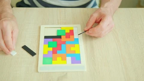 Senior man's engaged hands skillfully maneuver colorful wooden pieces brain.. Stock Footage 276714987