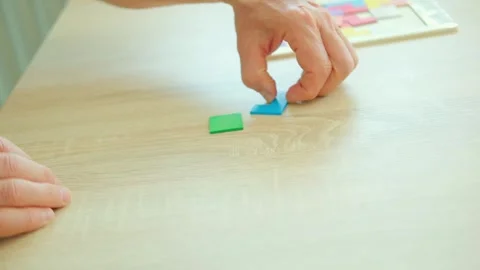 Senior man's engaged hands skillfully maneuver colorful wooden pieces brain.. Stock Footage 327876189