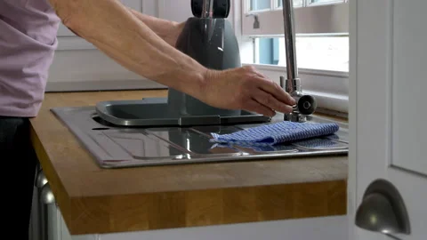 A senior man’s hand adding water to a kettle from a kitchen sink tap. Stock Footage 288337067