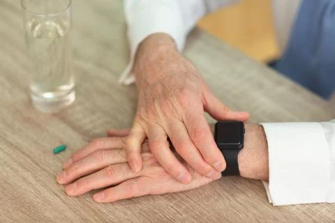 Senior Man's Hands Checking Smartwatch Before Taking A Pill, Cropped Фото