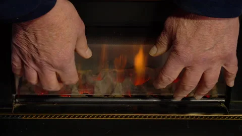 A senior man's hands warming in front of an old gas fire. Stock Footage 257209076