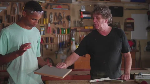 Senior master carpenter orienting apprentice at carpentry workshop. Mentor .. Video stock 246946306