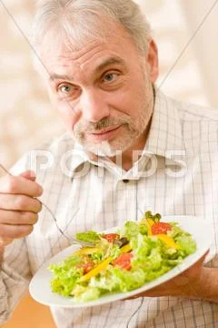 Senior mature man eat vegetable salad Stock Photos
