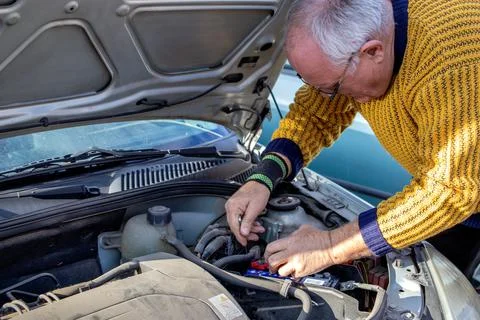 Senior mechanic worker checking and changing a car battery. 스톡 사진