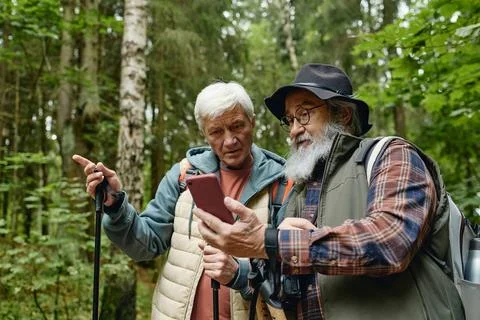 Senior Men Checking Navigation on Smartphone While Hiking in Forest Stock Photos