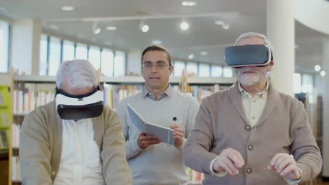Senior men using virtual reality glasses with teacher in library Stock-Footage 232623279