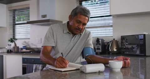 Senior mixed race man taking blood pressure in kitchen Stock Footage 147738403