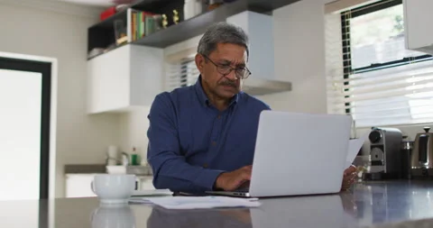 Senior mixed race man using laptop in kitchen Stock Footage 147738338