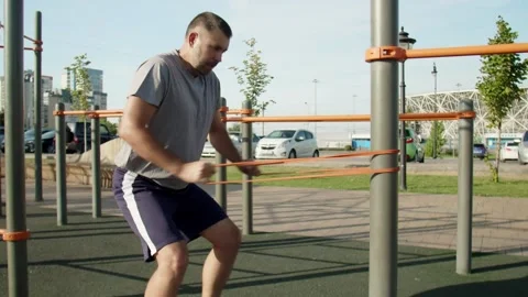 Senior muscular man doing pulling exercises with elastic band outdoors. Workout Stock Footage 143506175