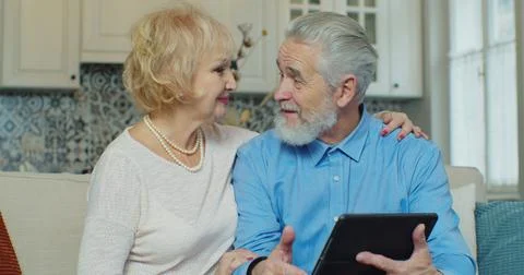 Senior old couple talking using digital tablet computer modern tech at home Foto stock