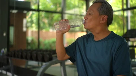 Senior old man drinking water after runner exercise running on the treadmill in  Stock Footage 274404865