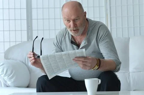 Senior old man reading newspaper at home Stock Photos