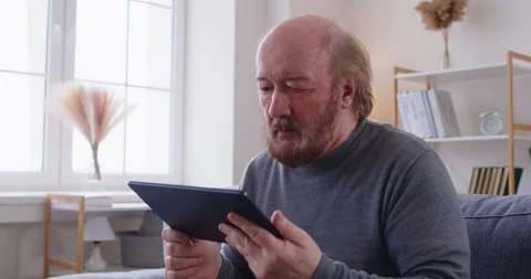 Senior old man with tablet, elder father learning how to use computer, choose Video stock 314967942