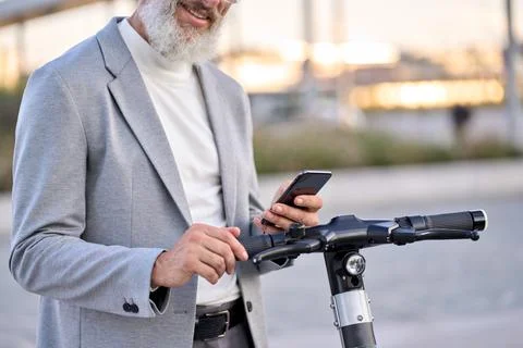 Senior old man using mobile app for bike rental renting bike in city park. Stock Photos