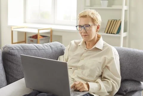 Senior older lady using applications on laptop computer screen, old mature woman Stock Photos