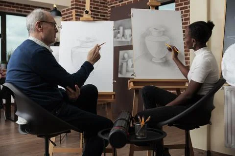 Senior painter teacher explaining sketching lesson to young student Stock Photos