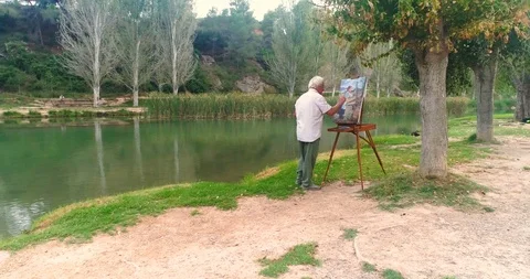 Senior painter in the woods by the river Stock Footage 124383999