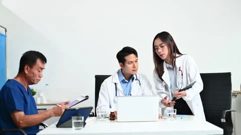 Senior patient meets with doctors using tablet and laptop in modern clinic... Stock Footage 312665911