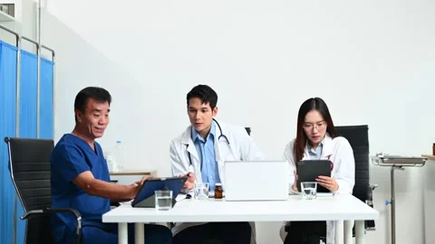 Senior patient meets with doctors using tablet and laptop in modern clinic... Video stock 313857903
