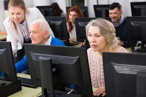 Senior people learning to use computers with young tutor 库存照片