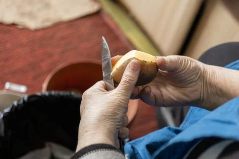 A senior person uses a sharp paring knife to remove skin from a fresh raw p.. Stock Photos