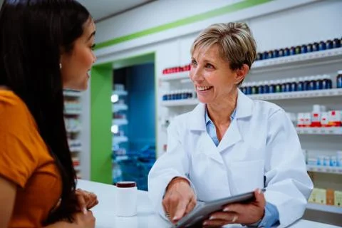Senior pharmacist explaining medication guide to mixed race client standing in Stock Photos