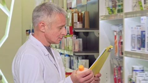 Senior pharmacist working, reading papers and examining medication Stock Footage 102715221
