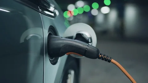 Senior is plugging in power cord to an electric car. Close up. 4K Видео 72680433